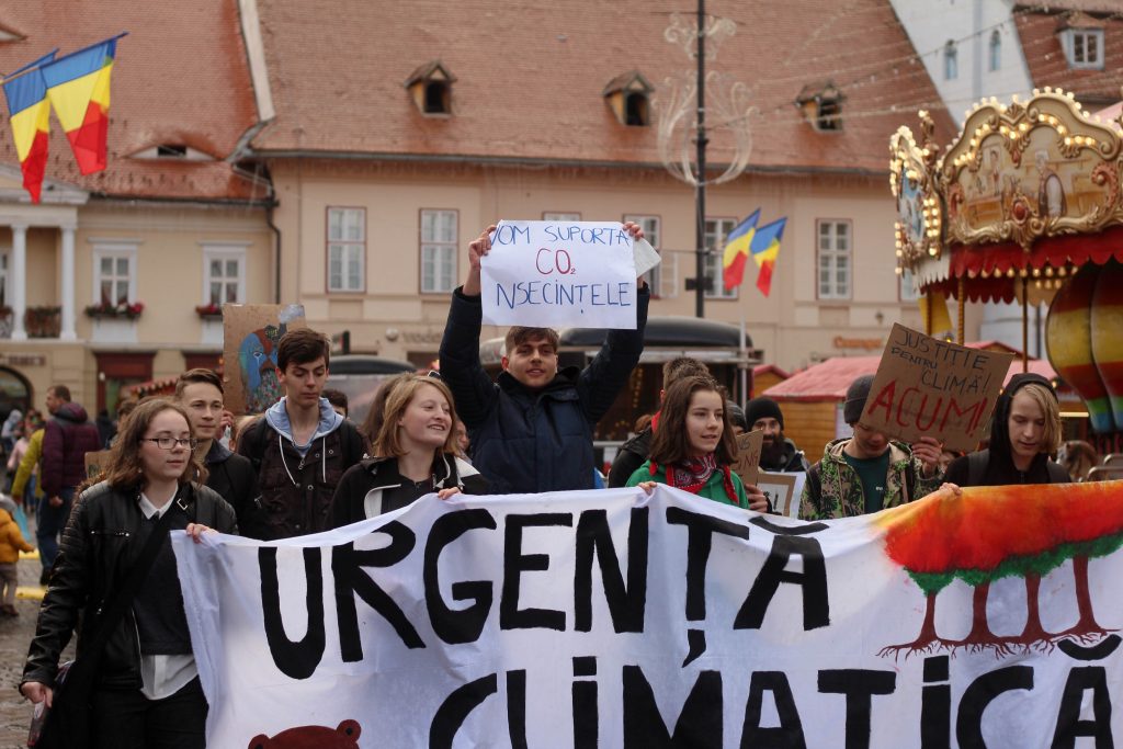 An image of climate strikers marching through a Christmas Market with a banner. 