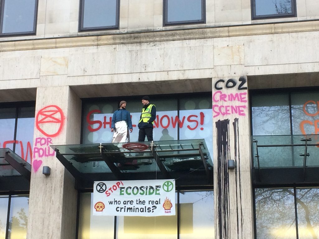 Image from the day of the protest, activists stand on the Shell headquarters' entrance, graffiti and banners cover the building.