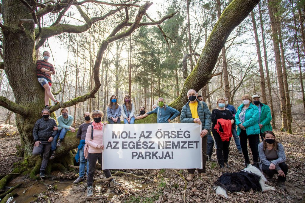 Eine Gruppe ungarischer Aktivisten im Wald und Park von Orseg steht vor einem Transparent gegen die Beteiligung von MOL.