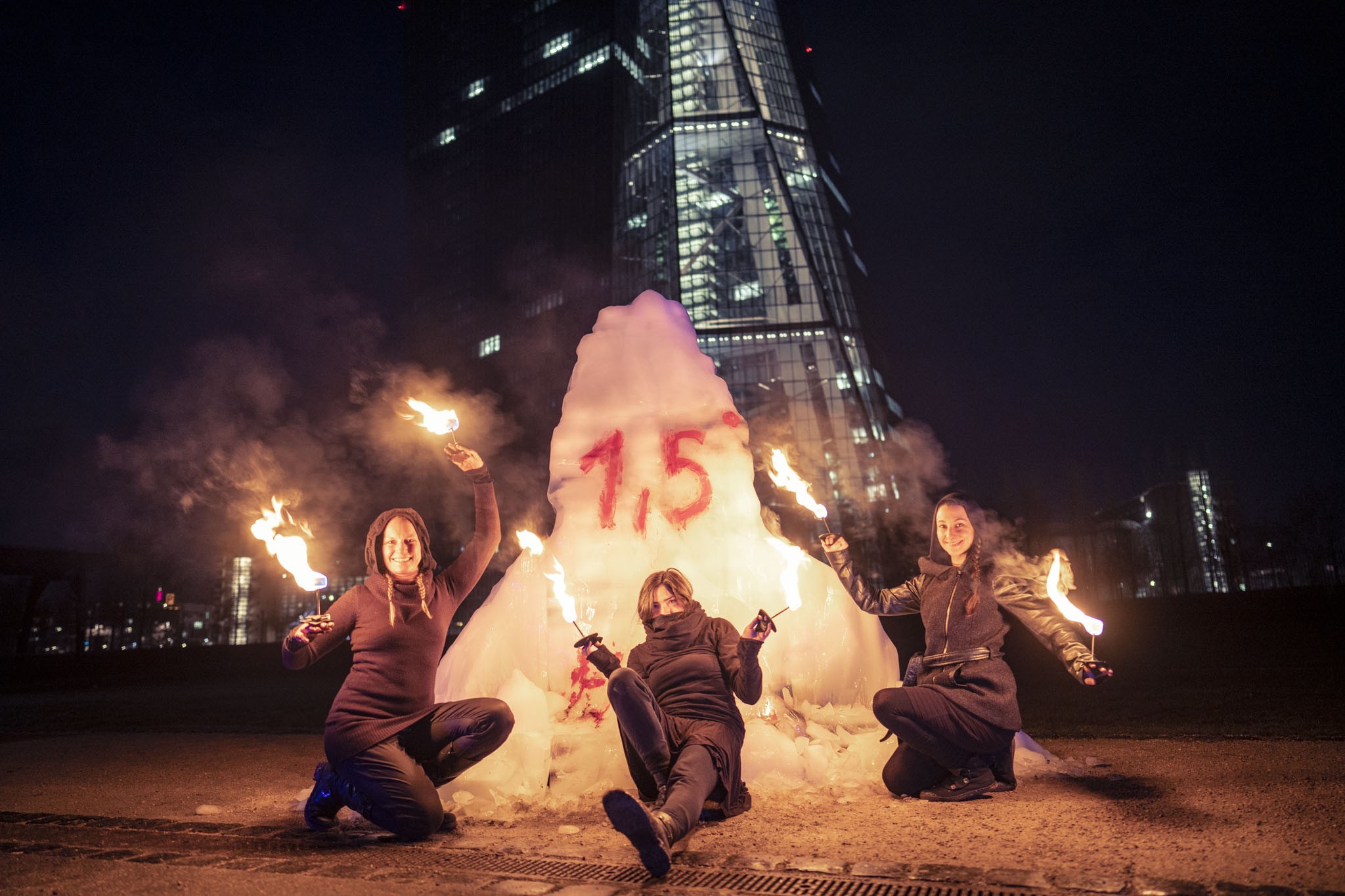Drei Aktivisten des KoalaKollektivs posieren mit einem Eisberg vor der EZB