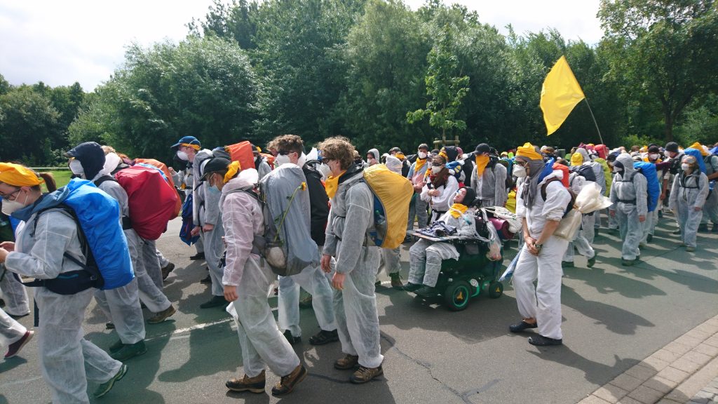 Ende Gelände-Aktivisten ziehen zusammen, gekleidet in Overalls und Masken