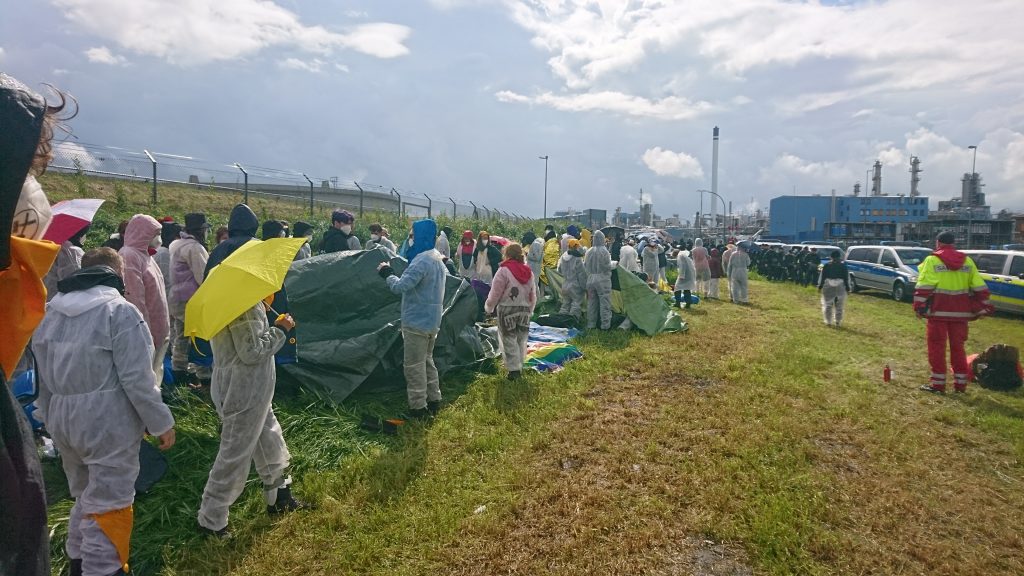 Ende Gelände activists set up tents and other banners together, dressed in white jumpsuits. 