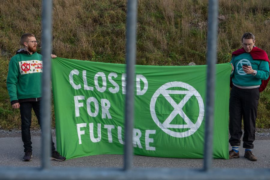 Two XR activists stand with a banner reading Closed For Future.